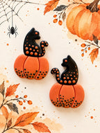 Polymer clay black cat on orange pumpkin earrings with dotted detail, a Halloween workshop example