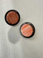 Halo Peach handmade polymer clay stud earrings with marbled peach centres in charcoal rims, on a white textured background