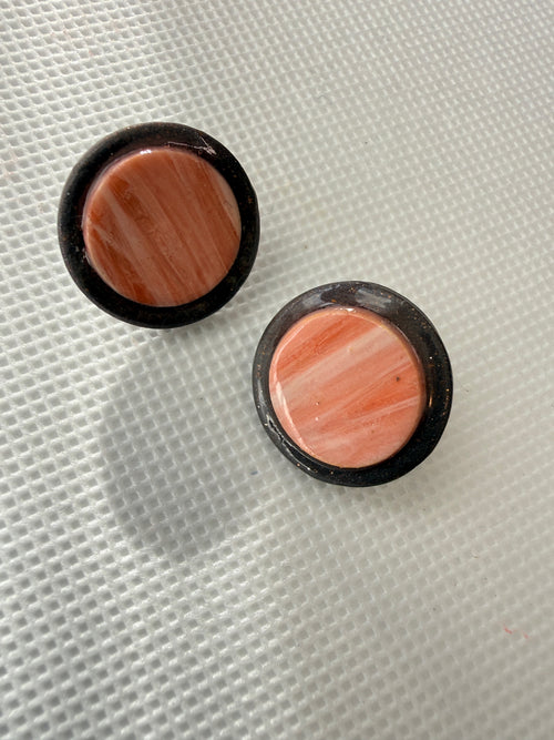 Halo Peach handmade polymer clay stud earrings with marbled peach centres in charcoal rims, on a white textured background