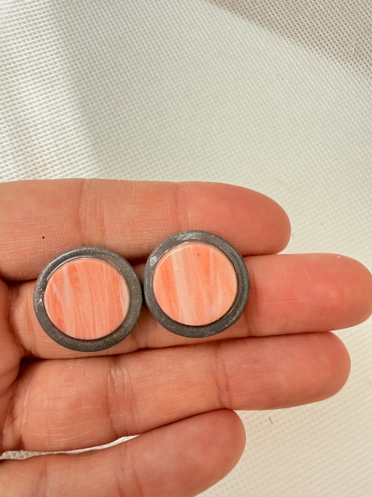 Halo Peach 2 cm polymer clay stud earrings held in a hand to show their size
