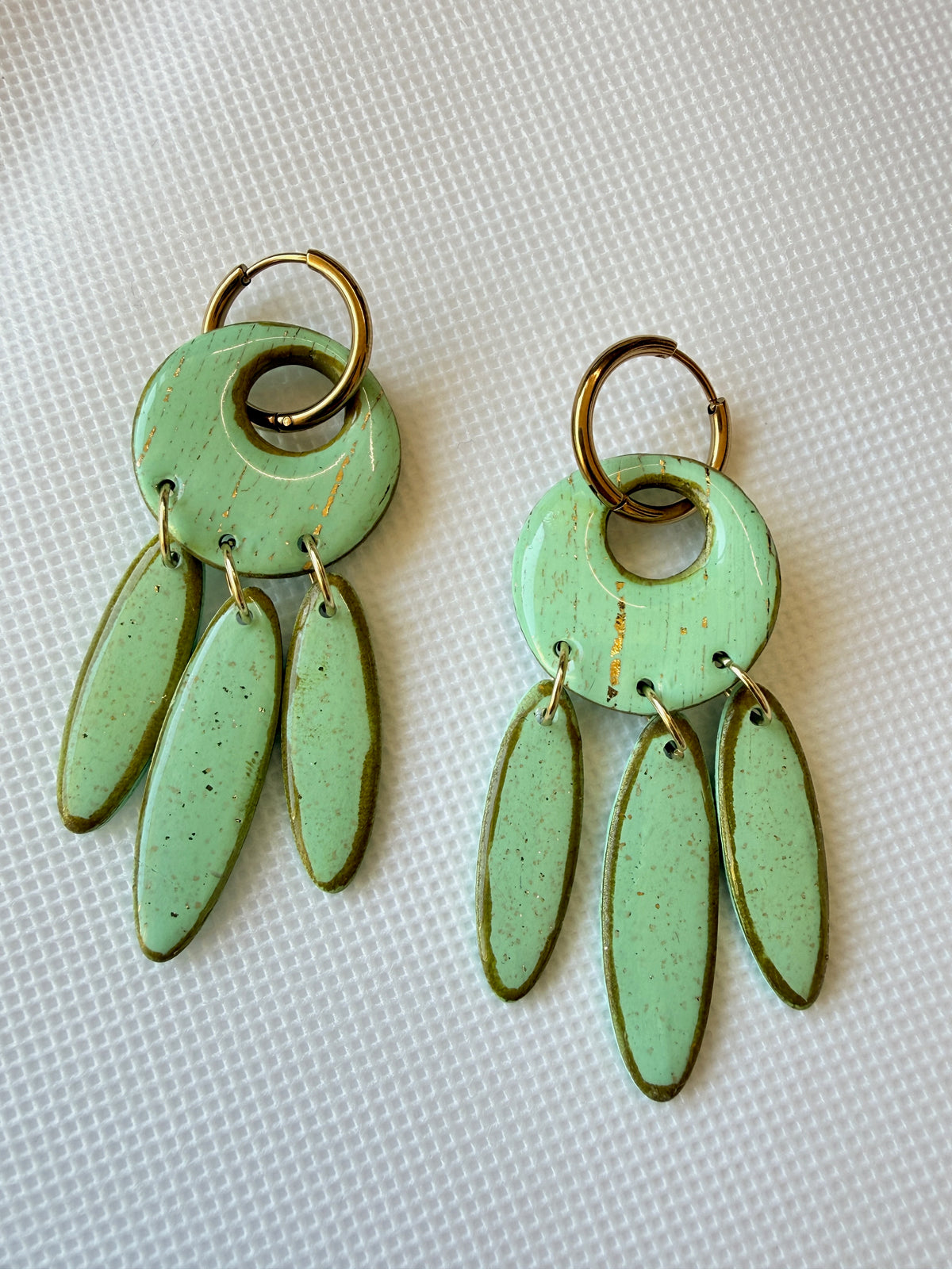 Willow Mint handmade polymer clay earrings with mint green leaf-shaped drops on 18k gold-plated hoops, laid flat on white